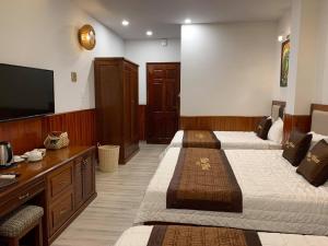 a hotel room with three beds and a flat screen tv at Hào Hoa Hotel Kon Tum in Kon Tum