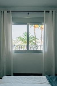 a bedroom with a window with a view of a palm tree at Cornisa Apartments in Patalavaca