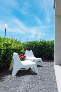 two white chairs sitting next to a plant at Cornisa Apartments in Patalavaca