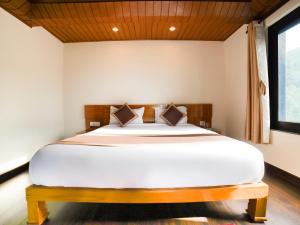 a bedroom with a large white bed with a wooden headboard at Boros Resorts Binsar in Almora