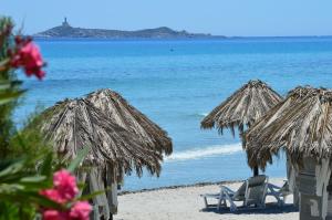 - deux chaises longues et des parasols sur une plage donnant sur l'océan dans l'établissement Residence Fenicia, à Villasimius