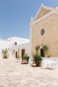 a courtyard of a white building with chairs and tables at Masseria Borgo San Marco in Fasano