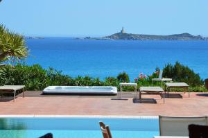 une piscine avec des chaises et une piscine dans l'établissement Residence Fenicia, à Villasimius