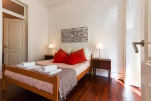 ein Schlafzimmer mit einem Bett mit roten Kissen in der Unterkunft Bairro Alto Classic by Homing in Lissabon