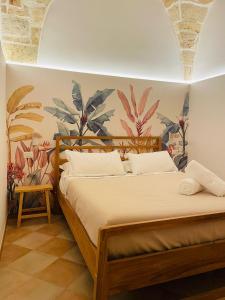 - une chambre avec un lit et une fresque murale de plantes dans l'établissement CASETTA CARENS nel centro storico di Nardò, à Nardò