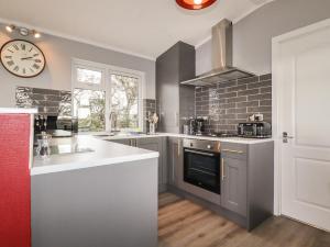 a kitchen with a sink and a clock on the wall at Sycamore Lodge in Helston