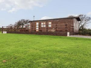 a wooden cabin in a field with a green field at Sycamore Lodge in Helston