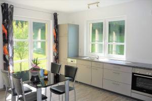 a kitchen with a table and chairs and windows at Ferienwohnung In der Ruhl in Schuttertal