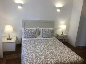 a hotel room with a bed and two lamps at Guarda Rios in Vila Nova de Milfontes