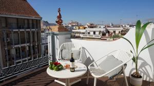 balkon ze stołem i krzesłami oraz butelką wina w obiekcie San Jorge Suites Triana w Sewilli