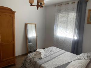 een slaapkamer met een bed, een spiegel en een raam bij Coronichi in Montefrío