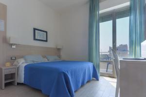 ein Schlafzimmer mit einem blauen Bett und einem Balkon in der Unterkunft Hotel Olympia in Senigallia