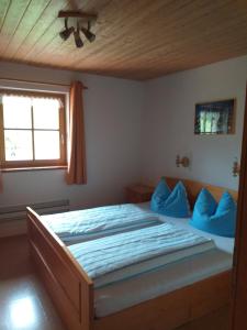 a bedroom with a bed with blue pillows and a window at Fronwieshäusl Gschoßmann Johanna in Ramsau