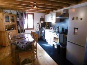 a kitchen with a table and a stove and a refrigerator at Le logis des cerfs in Puyvalador