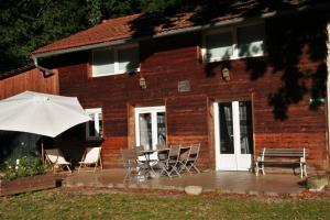 a patio with a table and chairs and an umbrella at A l'oree du bois - Gite in Hostun