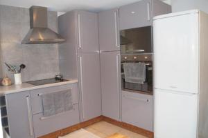 a kitchen with white cabinets and a refrigerator at A l'oree du bois - Gite in Hostun