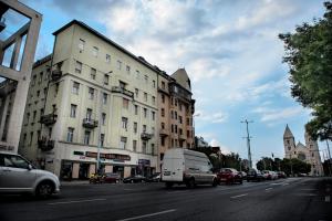 una furgoneta blanca conduciendo por una calle de la ciudad con edificios en Westend Hostel, en Budapest