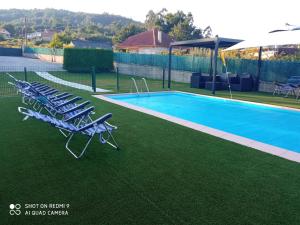 un grupo de tumbonas junto a la piscina en VILLA ANDURIÑA, casa con piscina cubierta, en Mondariz