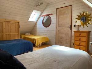 1 dormitorio con 2 camas, espejo y puerta en Gîte du Manoir du Cosquer en Pommerit-Jaudy