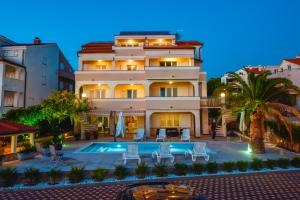 a large building with a swimming pool in front of it at Beachfront Apartments Tolo with Pool in Novalja