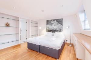 ロンドンにあるBeautiful 1 Bedroom Apartment in Victoriaのベッドルーム1室(ベッド1台付)が備わります。壁には絵画が飾られています。