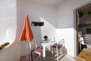 ポルシェスにあるApartamento Vila Mouriscaの白いテーブルと椅子の横に座るオレンジの傘