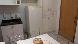 a kitchen with a table and a white refrigerator at Kit no Lago Norte CA 02 in Brasília