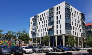 een groot wit gebouw met auto's geparkeerd op een parkeerplaats bij ESTUDIO IDEAL PARA VACACIONES Y TRABAJO in Vigo