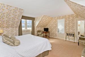 1 dormitorio con 1 cama blanca grande y escritorio en The Creggans Inn, en Strachur