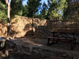 Otium Oasis Glamping & Camping في Hartebeest Rivier: سور خشبي مع مقعد وجدار حجري