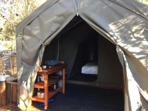 a tent with a bed and a table in it at Otium Oasis Glamping & Camping in Hartebeest Rivier