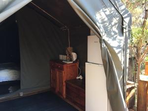 Otium Oasis Glamping & Camping في Hartebeest Rivier: غرفة فيها ثلاجة وسرير في خيمة