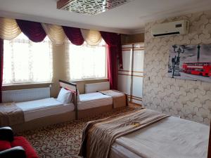 a bedroom with two beds and two windows at Demosan City Hotel in Konya