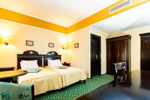 ティミショアラにあるHotel Koronnaのベッドとテーブルが備わるホテルルームです。