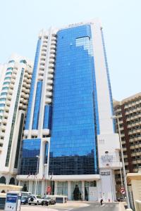 Grand Continental Hotel في أبوظبي: مبنى طويل والنوافذ الزرقاء في المدينة