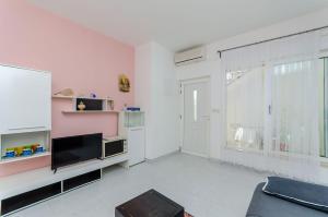 - un salon avec une télévision et une grande fenêtre dans l'établissement Apartments Zdenka, à Okrug Donji