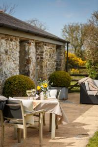 a table and chairs with flowers on a patio at The Granary at Cornish Barn Holidays in Truro