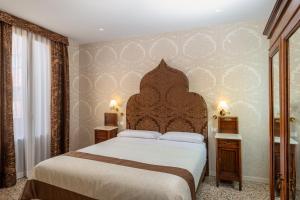 a bedroom with a large bed with a wooden headboard at Hotel Villa Rosa in Venice