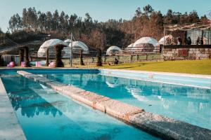 Ein Schwimmbad mit Kuppeln und Zelten im Hintergrund in der Unterkunft Guimaglamp in Guimarães