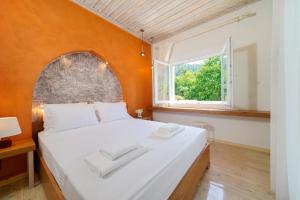 a bedroom with a large white bed with an orange wall at Villa Gjoni in Limenas