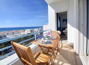 een tafel op een balkon met uitzicht op de oceaan bij COLINA FÉRIAS- Garagem & WIFI in Quarteira