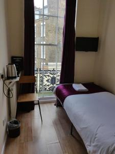 Un dormitorio pequeño con una cama y una ventana. en Kings Cross Hotel London, en Londres