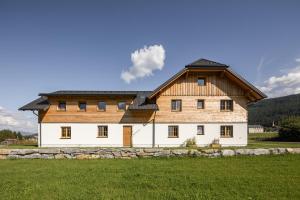 a large house with a wooden roof on a field at Appartements HOAMATGFÜHL in Sankt Margarethen im Lungau