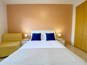 a bedroom with a bed with blue pillows and a chair at Terracotta terrace in Barcelona