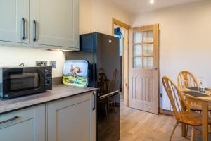 a kitchen with a microwave refrigerator and a table at Loaf Tin in Kendal