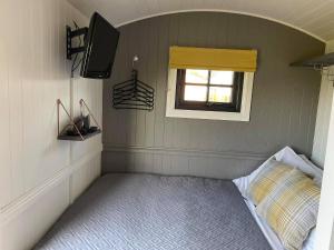a small room with a bed and a window at On the Moor Shepherds Huts in Bodmin