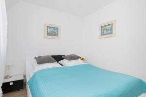 a bedroom with a blue bed with two pictures on the wall at JANTAR APARTAMENTY -Port Kołobrzeg ul. Westerplatte in Kołobrzeg