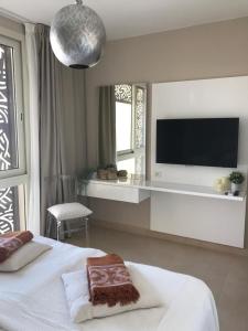 Jutta Deluxe 2,5-Bedroom-Apartment Mangroovy-M10 El Gouna في الغردقة: غرفة نوم بسرير وتلفزيون بشاشة مسطحة