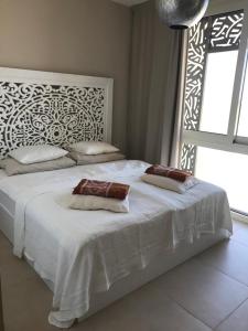 Jutta Deluxe 2,5-Bedroom-Apartment Mangroovy-M10 El Gouna في الغردقة: غرفة نوم بسرير ابيض وعليها وسادتين