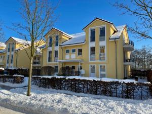 ein gelbes Haus im Schnee in der Unterkunft Schloonseevillen - FeWo 13 in Bansin